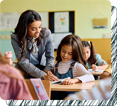 Teacher pointing out some information to a young student at their desk.